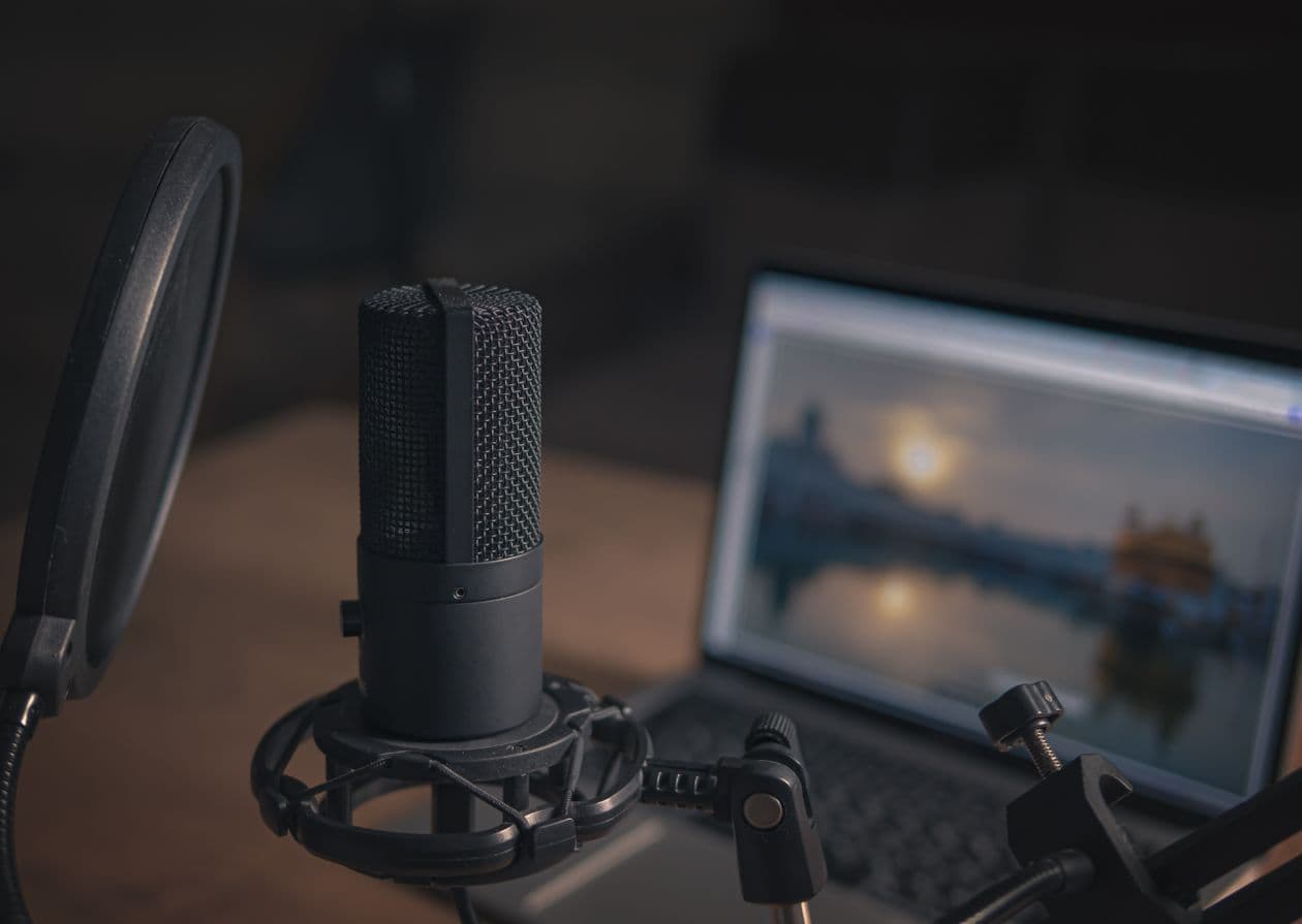 Micro de podcast sur son support, devant un ordinateur portable allumé